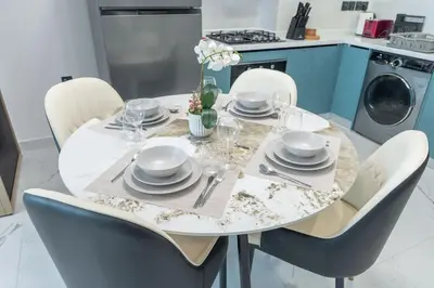 a white dining room table with chairs and a white table and chairsktop at StayShort - Al Barsha Apartment Sleeps 2 with Private Balcony in Dubai