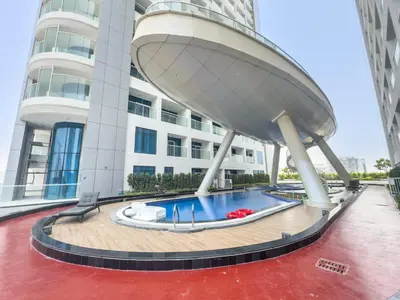 a building with a swimming pool in front of it at StayShort - Al Barsha Apartment Sleeps 2 with Private Balcony in Dubai