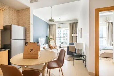 a kitchen and a living room with a table and chairs at Water View I Chic 1BR I Mayfair I 3 Sleeps I Fast Wi-Fi I Walkable Area in Dubai
