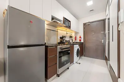 a kitchen with a stainless steel refrigerator and a dishwasher at Luxury Studio with Gym, Pool & Badminton Court in Dubai