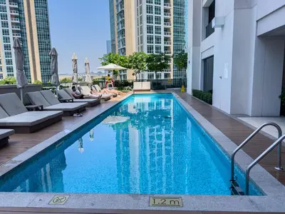a swimming pool in a building with people laying on chairs at Beautiful 2BR with Burj Khalifa Views in Dubai