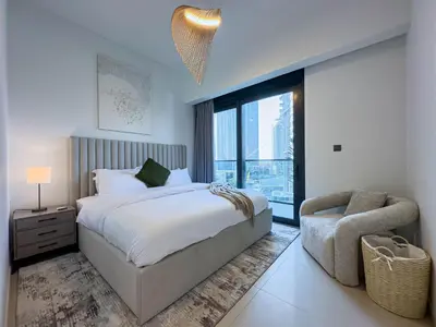 a bedroom with a bed and a chair and a window at Beautiful 2BR with Burj Khalifa Views in Dubai