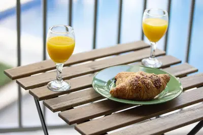 two glasses of orange juice and a plate of food on a wooden table at Cozy Studio Near Burj Khalifa Sleeps 3 in Dubai