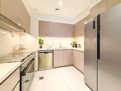 a kitchen with wooden cabinets and a stainless steel refrigerator at Act 1 Act 2 Towers, Luxury 4BR, Full Burj Khalifa View Balcony, Pool, Gym in Dubai