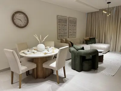 a living room with a table and chairs and a clock at Binghatti Galaxy 2 in Dubai