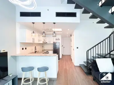 a kitchen and living room with a counter and stools at Urban Duplex Hideaway l Gym, Pool & Balcony in Dubai