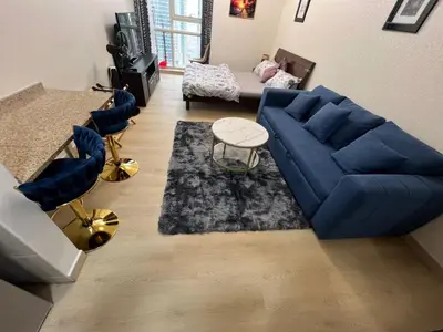 a living room with a blue couch and a rug at Cozy Studio with Sofa bed beside DMCC Metro & Dubai Marina in Dubai