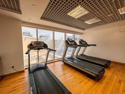 a gym with three treadmills in a room at Cozy Studio with Sofa bed beside DMCC Metro & Dubai Marina in Dubai