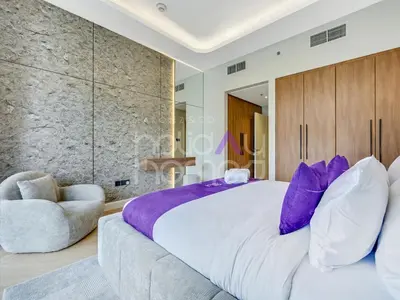 a bedroom with a large bed and a chair at Modern 2BR Gem Full Golf Views & Pool in Dubai