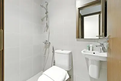a white bathroom with a toilet and a sink at 2BR plus Maid CF7 B Stylish Stay with Large Balcony in Dubai