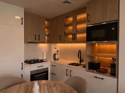 a kitchen with white cabinets and a table with chairs at 1 Bedroom Apartment in Liva by the S Holiday Homes in Dubai