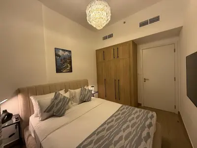 a bedroom with a large bed and a chandelier at 1 Bedroom Apartment in Liva by the S Holiday Homes in Dubai
