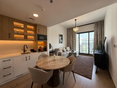 a kitchen and living room with a table and a couch at 1 Bedroom Apartment in Liva by the S Holiday Homes in Dubai