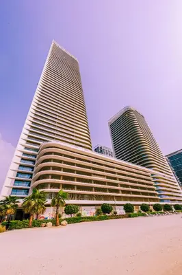 two tall buildings with palm trees in front of them at Sea Breeze apartment in Grand Bleu - private Beach in Dubai
