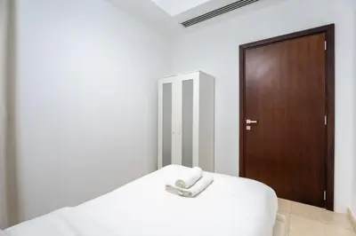 a bedroom with a white bed with a wooden door at GuestReady - Luxury 2BD w/ balcony | Business Bay in Dubai
