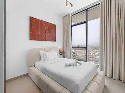 a bedroom with a bed and a couch and a window at Upscale 2Bedroom with Private Balcony Pool in JVC in Dubai