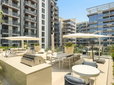 an outdoor patio with tables and chairs and umbrellas at 1BR Luxury Stay in Sobha Hartland in Dubai