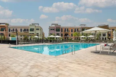 a large swimming pool with umbrellas and buildings at Prestige Jumeirah 4BR Villa with Rooftop and Private Garden in Dubai