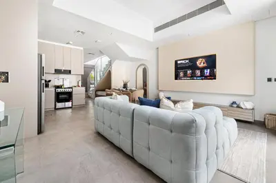 a living room with a large couch and a kitchen at New 2.5 BR Villa With PS5 and Garden Near Dubai Mall in Dubai