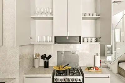 a kitchen with white cabinets and a stove top oven at New 2.5 BR Villa With PS5 and Garden Near Dubai Mall in Dubai
