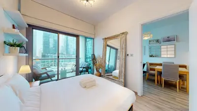 a bedroom with a large white bed and a dining room at Iris Blue - Colourful One Bedroom in The Marina in Dubai