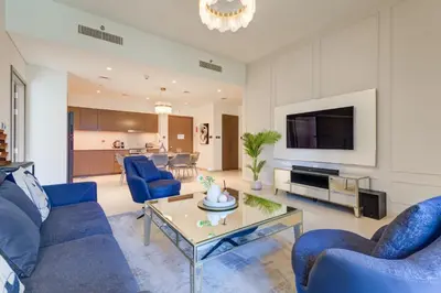 a living room with blue couches and a tv at Vacationer l Vibrant 2 Bedroom l Pool with Burj Khalifa View in Dubai