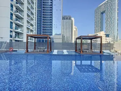 a swimming pool with two pavilions in a city at Studio One - Sleek One Bedroom with City View in Dubai