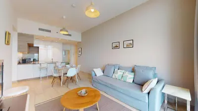 a living room with a blue couch and a table at Studio One - Sleek One Bedroom with City View in Dubai