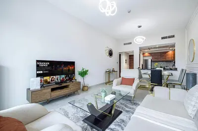 a living room with white furniture and a flat screen tv at Lush 1BR Oasis in JVC With Gym & 5min to Circle Mall in Dubai