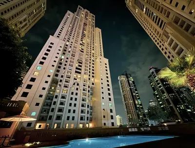 a tall white building with a pool in front of it at 4 Bedroom Sea View Apartment in Jumeirah Beach Residence in Dubai