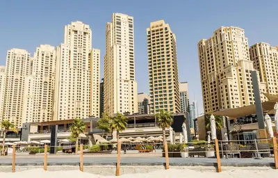 a skyline of tall buildings with palm trees in the sand at 4 Bedroom Sea View Apartment in Jumeirah Beach Residence in Dubai
