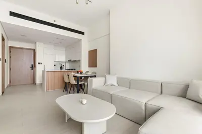 a living room with a white couch and a table at Vayk - Modern 1BR Apartment in JVC in Dubai