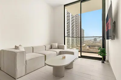 a white living room with a couch and a table at Vayk - Modern 1BR Apartment in JVC in Dubai