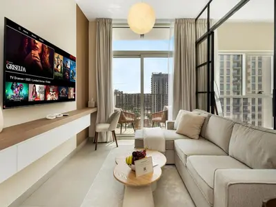 a living room with a couch and a tv at Modern 1BR with Cinema, Pool and Gym Dubai Hills in Dubai