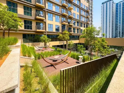 a building with a garden with a table and benches at Modern 1BR with Cinema, Pool and Gym Dubai Hills in Dubai