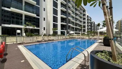 a swimming pool with chairs and a building at Peaceful 1BR with Community View, Quick Downtown and Golf Club Access, Azizi Riviera 34, Al Merkadh by Deluxe Holiday Homes in Dubai