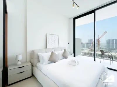 a white bedroom with a bed and a large window at Stylish 1BR Retreat in Binghatti Amber l Balcony in Dubai