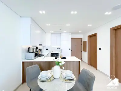 a kitchen with a table and chairs and a kitchen with white appliances at Chic Binghatti Amber 1BR l Balcony & Comfort in Dubai