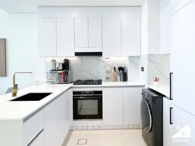 a white kitchen with white cabinets and a dishwasher at Chic Binghatti Amber 1BR l Balcony & Comfort in Dubai