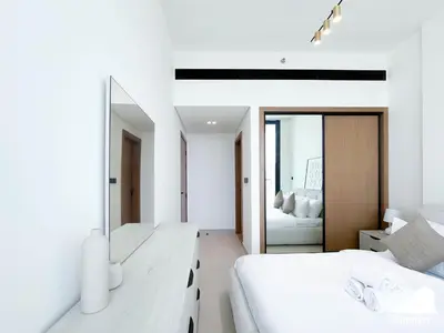a white bedroom with two beds and a mirror at Chic Binghatti Amber 1BR l Balcony & Comfort in Dubai