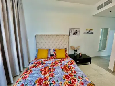 a bedroom with a bed with yellow and red pillows at Stunning studio with balcony close to metro in Dubai
