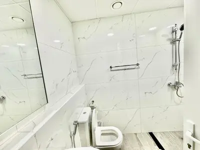a white bathroom with a toilet and a shower at Stunning studio with balcony close to metro in Dubai