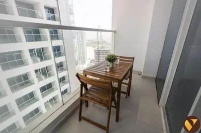 a table and chairs on a balcony with a large window at Vogue Arjan Opalz by Danube near Science Park, Studio Apartment with Balcony and Vibrant Community View, Access to all Amenities in Dubai