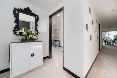 a hallway with a mirror and a dresser with flowers on it at Waterfront Luxury 2 Bed in Marina Mall Hotel in Dubai