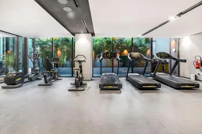 a gym with several treadmills and elliptical machines at Brand New Luxury Studio in JVC in Dubai