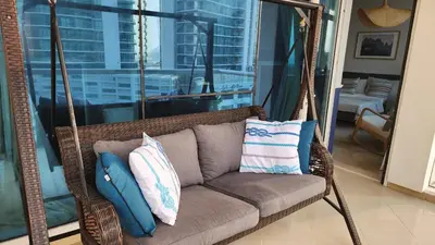 a wicker swing with pillows on it in a living room at Sea Breeze Luxury 2BR, Dubai Marina, Big Terrace, Near Beach, Pool access, by Stay Vista! for up to 6 Guests in Dubai