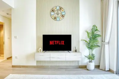 a tv sitting on a white dresser in a living room at PVH - Charming 1 BR - Lotus Creek Beach in Dubai