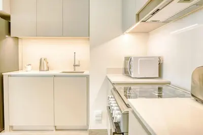 a kitchen with white cabinets and a microwave at PVH - Charming 1 BR - Lotus Creek Beach in Dubai