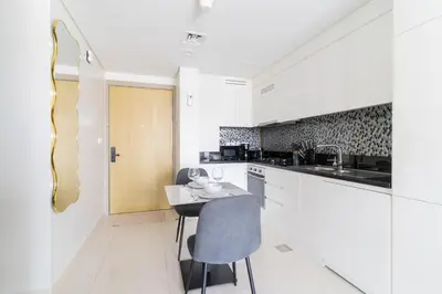 a kitchen with white cabinets and a table and chairs at Modern 1BR in Aykon City - Near Burj Khalifa & Canal in Dubai