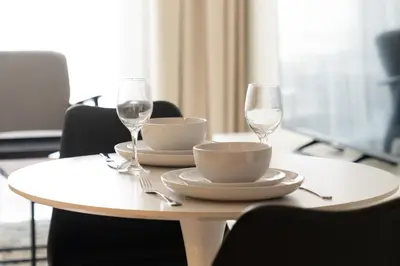 a white table with two wine glasses and a table with chairs at Business Bay 1br with High-Floor Views in Dubai